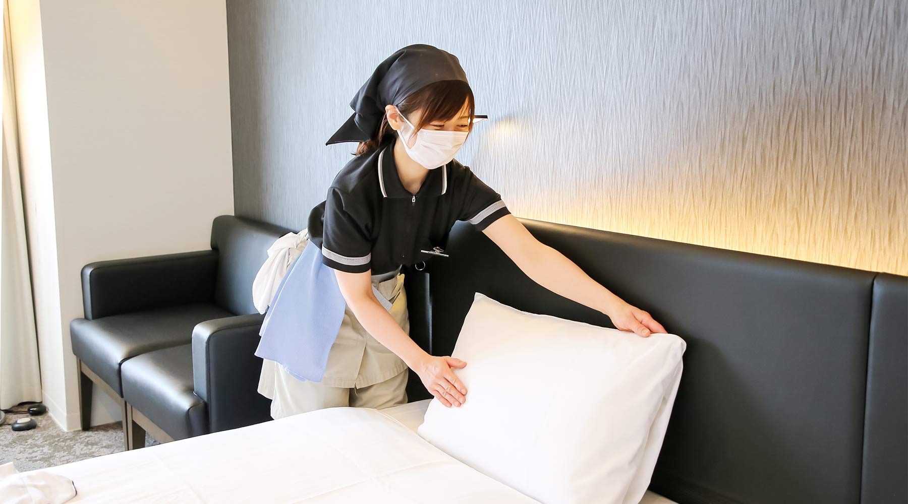 ホテルのルームでベッドメイキングにあたるスタッフのイメージ